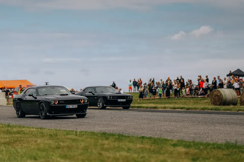 Dva černé Dodge Challengery vedle sebe na startu dráhy