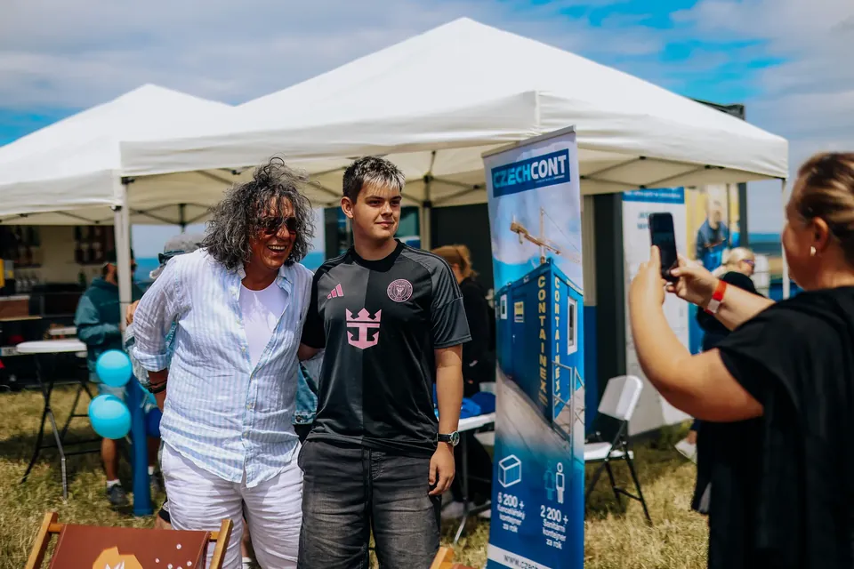 Návštěvníci festivalu se fotí u stánku partnera