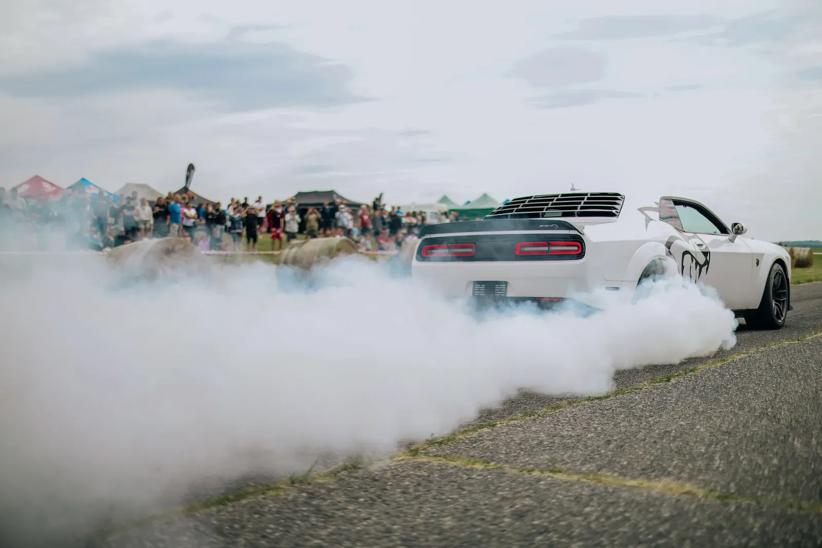 Bílý Dodge Challenger v oblaku kouře z pneumatik při burnoutu na dráze