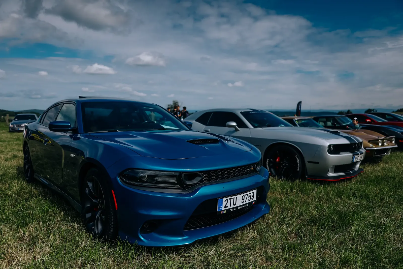Modrý Dodge Charger a stříbrný Dodge Challenger zaparkované na trávě na US Cars Fest 2026